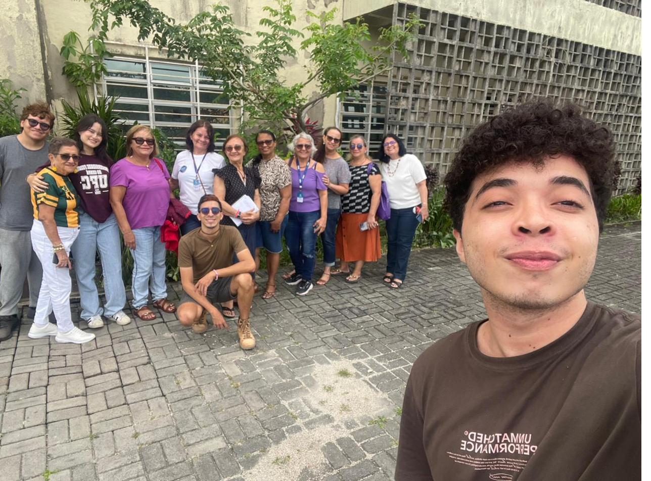 Grupo de voluntários e participantes posando para foto em área externa do campus.